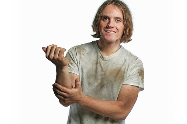 A long-haired blonde white man with dirt on his face and hands.